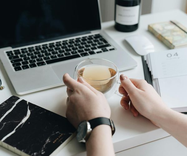 Calendar and a cup of tea on a desk symbolizing daily planning and routine.